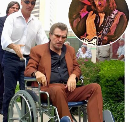 Gone is the Waylon Jennings the world remembers — not the outlaw with a booming voice and a guitar slung across his shoulder, but a man weathered by time, seated in a wheelchair, facing life with the same grit that marked every song he ever sang.